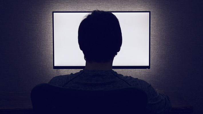 A person in dark room looking at monitor